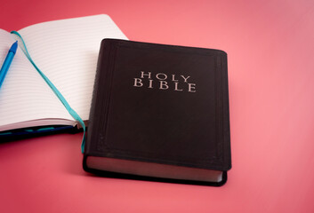 The Holy Bible with a Notebook to Study on a Bright Pink Background
