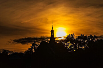  Sandomierz , zabytkowy kościół  podświetlony przez zachodzące słońce . Czarne sylwetki...