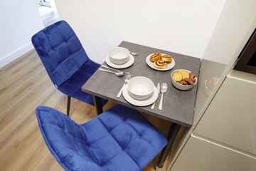 Stół w nowoczesnej stylowej kuchni w apartamencie z talerzami i ciasttkiem - obrazy, fototapety, plakaty