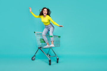 Full body photo of pretty brunette hair millennial lady ride trolley wear top jeans shoes isolated on teal color background