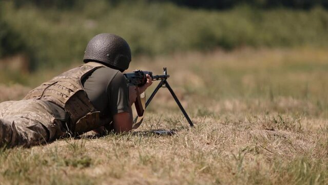 Armed military man unloading machine gun while lying with gun, soldier lying with gun, Military, Army war concept, ready to attack, Corps machine gun crew shooting, Army gunner attacking