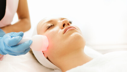 Beautician cosmetologist doing facial skin procedure with electroporation device in a beauty clinic...