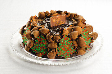 delicious chocolate christmas cake, with chocolate shavings and christmas trees on a plate, with a plaque saying 