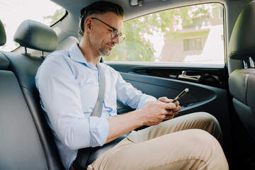 European grey man using mobile phone while going at car