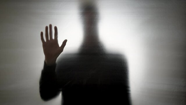 Blurred silhouette of a man with his hand raised up. The concept of horror, mental health.