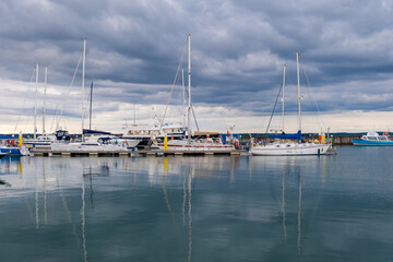 Fototapeta na wymiar Sailing boats in a calm harbour with reflections on the water, UK