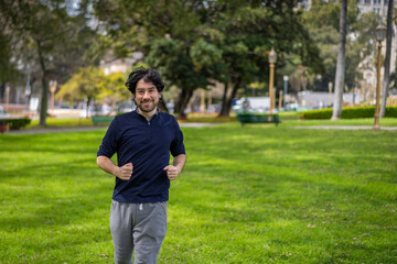 Portrait of handsome attractive mature bearded athletic latin man guy 40s in casual blue t-shirt running at a park