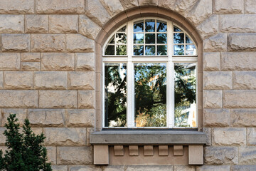 Arched window with a white frame and a reflection of trees against a beige slab wall. From the Window of the World series.
