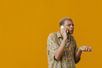 Blonde young man gesturing and talking on cellphone