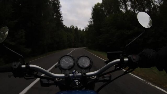 ride on a retro motorcycle on an asphalt forest road on a cloudy day in autumn. Dramatic trip.