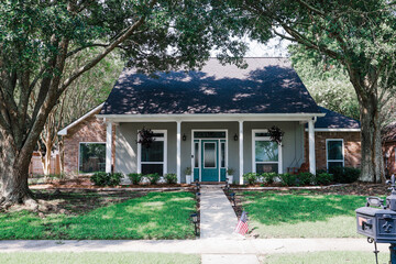 A front view of an Acadian renovated home with columns, sidewalks and a colorful front door recently purchased with the changing real estate market