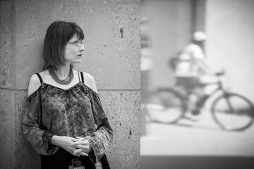 Eine hübsche Frau steht an einer Wand und beobachtet einen Fahrradfahrer, der sich im Fester...