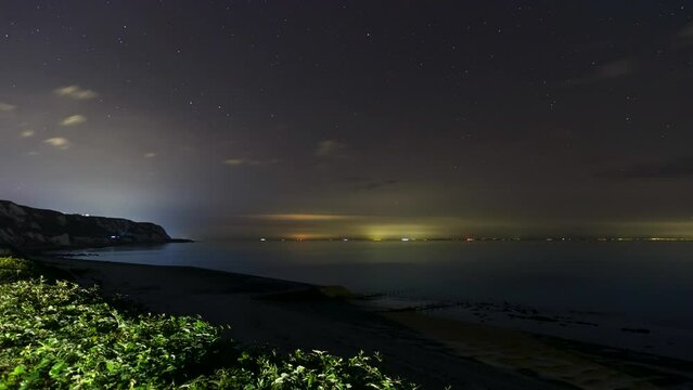 Time lapse shot of the cliffs at Weams Bay at night with stars in the sky and ships on the horizon