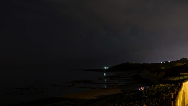 Time lapse shot of the cliffs at Weams Bay at dusk with moon and Martello tower in the background.