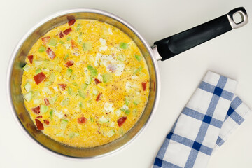 Scrambled eggs with squash and tomato in pan.  Top view.