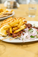 Fried meat souvlaki, fresh vegetables, pita bread, tzatziki sauce and french fries, traditional greek food served in cafe