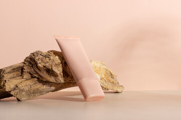 Face and body skin care products on a beige background next to a wooden branch. Professional cosmetics for skin care. Organic cosmetics. Cosmetics for women with natural ingredients. Copy space