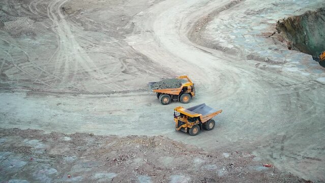 Heavy mining dump trucks driving along the opencast open mine pit, slow motion