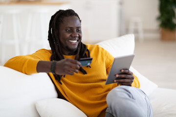 Smiling Black Man Shopping Online With Digital Tablet And Credit Card