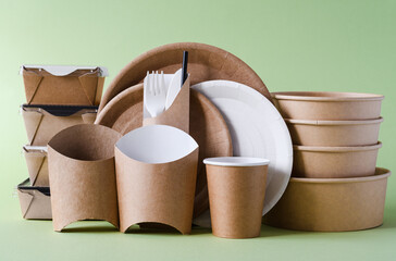 Biodegradable paper food delivery packaging on a green background. The concept of using eco-friendly materials to protect nature.