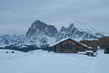 Fototapeta na wymiar Cottage in the snow with mountains in the background