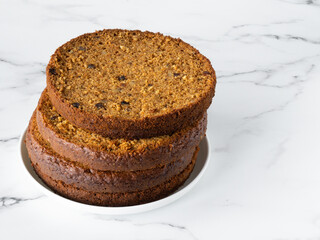 Preparation of layered carrot cake. Layers on a white plate on a marble table. White background, copy space