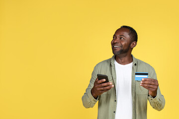 Happy adult black man in casual with credit card and smartphone enjoy shopping online