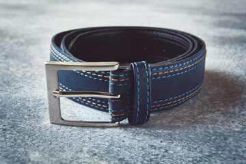 Stylish leather blue belt on gray background, close up, stylized
