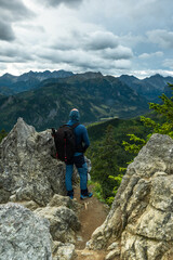Naklejka na ściany i meble Solo hiker standing on edge of rocks in mountains