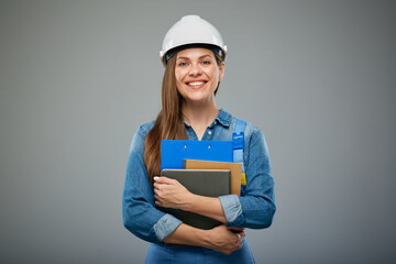 Woman engineer student in safety helmet and overall holding books and clipboard. Isolated female builder portrait.