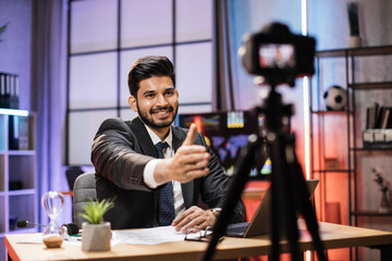 Confident skilled arab trader or office worker sitting in front of video camera in online meeting and greetings to his colleague imitating handshake.