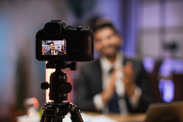 Focus on camera screen of smiling successful arab skilled bearded businessman in formal wear recording new video for his internet business course and clapping hands.