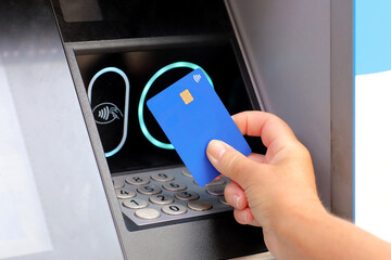 female hand with card by ATM. hand with credit card withdrawing money from ATM using NFC...