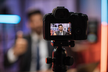 Focus on camera screen of smiling successful arab skilled bearded businessman in formal wear recording new video for his internet business course and showing thumb up.
