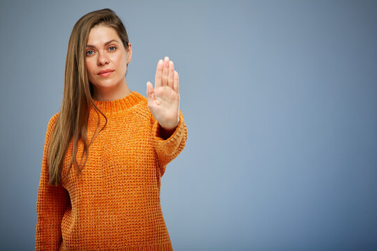 Woman in casual orange sweater doing stop gesture with hands. isolated female portrait on blue.