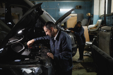 Side view portrait of two mechanics fixing trucks in garage workshop, copy space