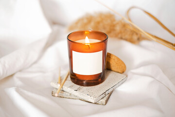 Cozy candle in jar with natural elements. Dry reeds boho style. Burning scented candle. Spa salon...