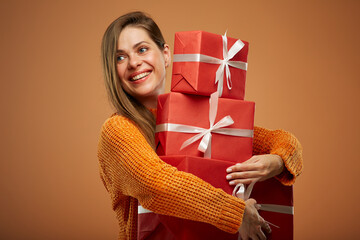 Happy woman in winter orange sweater holding stack of red gift boxes. Isolated female portrait in christmas style..