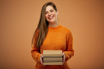 Smiling woman in orange sweater holding books stack. isolated portrait .