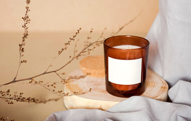 Meditation space with candle. Burning candle on wooden coaster. Warm aesthetic composition with dry boho branch and grey fabric. Home comfort, spa, relax and wellness concept. High quality photo