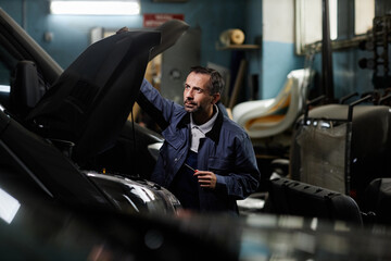 Side view portrait of mature car mechanic repairing trucks in garage with accent light, copy space
