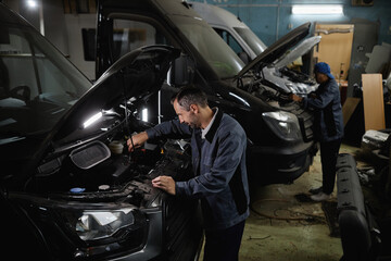 Side view at car mechanics repairing vans and trucks in garage shop or camper factory