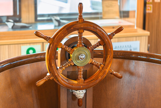 Close-up of a fake varnished wooden ship's wheel called a helm steered by a helmsman tied with a sailor's coil knot and used to change the rudder's angle so that the pirate's ship can turn on the sea.