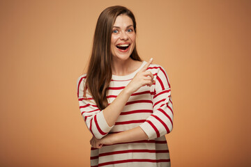 Smiling happy woman in casual striped sweater pointing finger at copy space. Isolated female portrait.