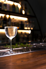 A misted glass of refreshing alcoholic drink on a bar counter. Vertical orientation. Selective focus.