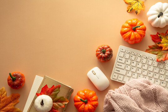 Autumn office workspace. Keyboard, laptop, notebok with autumn clothes and fall decorations - pumpkin, leaves and other. Fall flat lay.