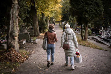 Mother and daughter visiting family graves in the cementary on All Saints' Day November 1. Blurred background. All Souls' Day.