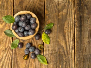 Foto op Plexiglas Blue plum in a bowl on a wooden table. Fruit background with copy space. © Максим