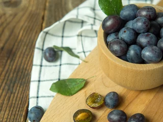 Foto op Plexiglas Blue plum in a bowl on a wooden table. Fruit background with copy space. © Максим