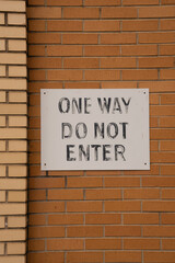 One way do not enter sign on a brick wall.  Vertical view. 